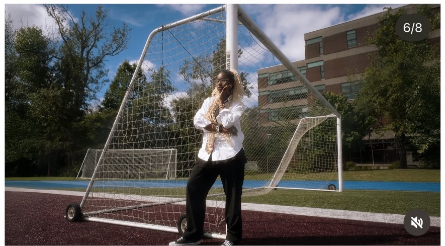 Anna poses in front of a full-size soccer goal in midday sun