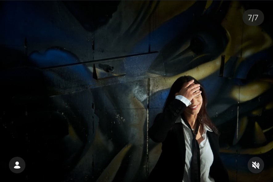 Sara Bic shielding her face from the light in a candid mural frame