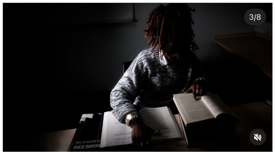 Stellae studies a Richard Serra book in low light at a desk