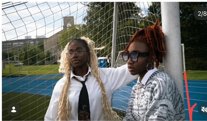 Anna and Stellae lean against a soccer goalpost on a school field