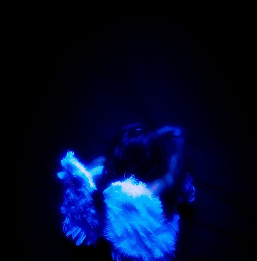 Yvette in the AGAPE sequence under blue-black lighting